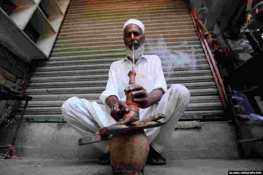 A man smokes a water pipe in Peshawar, Pakistan, on May 30.&nbsp;