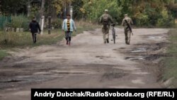 Українські військові йдуть з позицій до магазину по вулиці Миру у фронтовому селищі Кримське, вересень 2021 року