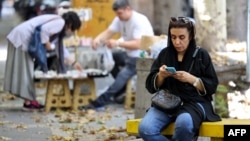 Tehranda qadın mobil telefonunu yoxlayır.