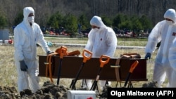 Cemetery workers wearing protective gear bury a coronavirus victim at a cemetery on the outskirts of St. Petersburg, Russia, on May 6.