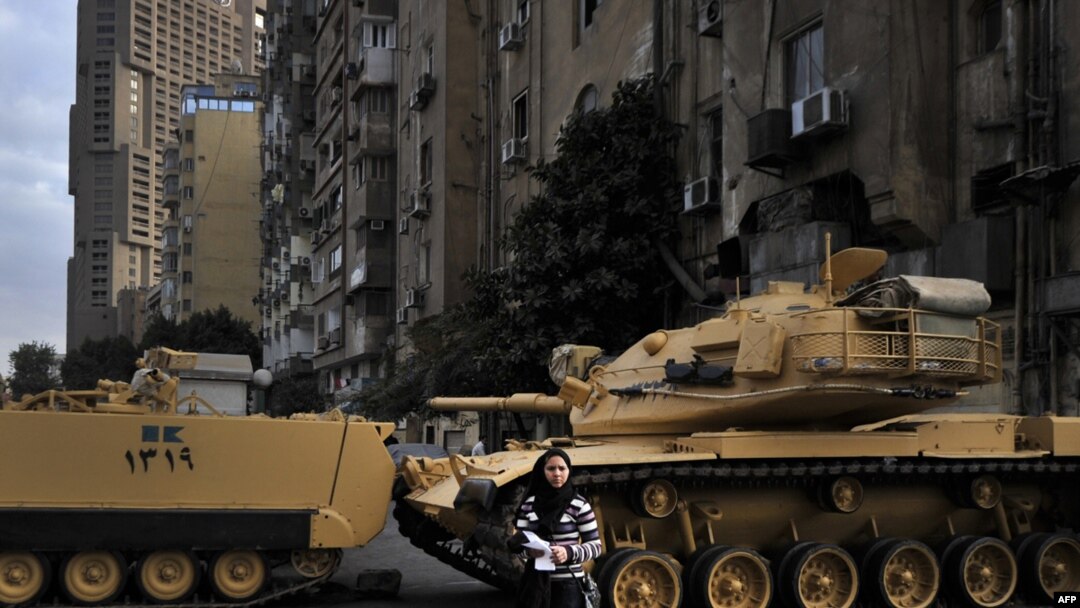 An Egyptian woman stands in front of tanks blocking the street outside the state television building during a demonstration by Coptic Christians in Cairo on March 10.
