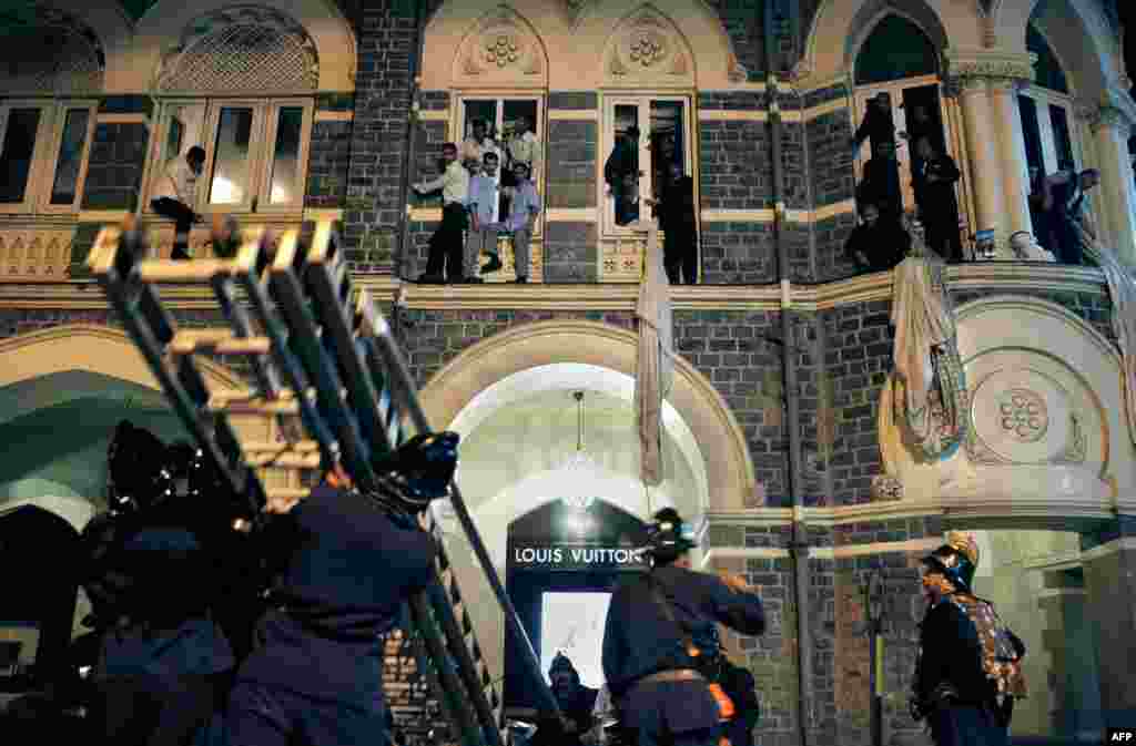 Employees and guests of the Taj Mahal hotel are rescued by firefighters as fire engulfs the top floor.