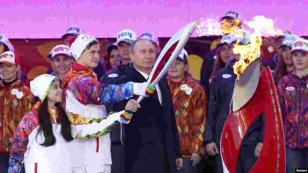 Russian President Vladimir Putin (center), ice skaters Lina Fyodorova (left) of Moscow and Maksim Miroshkin (second left) of Yekaterinburg mark the start of the Sochi 2014 Winter Olympic torch relay in Moscow. (Reuters/Sergei Karpukhin)