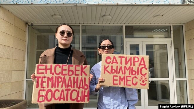 Активисты, пришедшие поддержать Темирлана Енсебека, держат плакаты, надписи на которых призывают освободить его. 9 апреля 2025 года