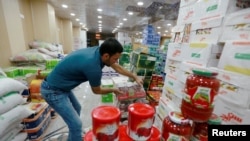 A shop worker arranges the cans of Iranian tomato paste at a super market in the city of Najaf, Iraq October 7, 2018. Picture taken October 7, 2018. REUTERS/Alaa Al-Marjani