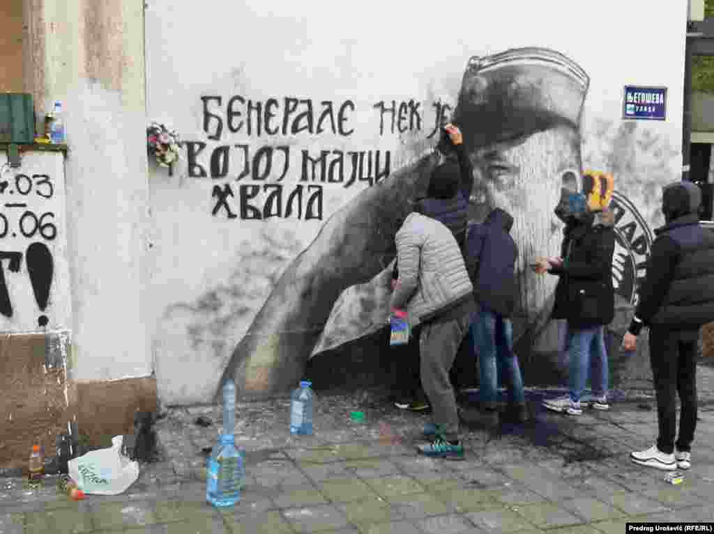 Un graffiti cu chipul criminalului de război Ratko Mladic este curățat de membrii unui grup de dreapta, la scurt timp după ce a fost aruncată vopsea neagră pe el, în Belgrad, Serbia.