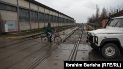 Një person kalon me biçikletën e tij shinat e trenit, që gjenden afër një lagjeje të banuar kryesisht nga pjesëtarët e komunitetit rom, ashkali dhe egjiptian.