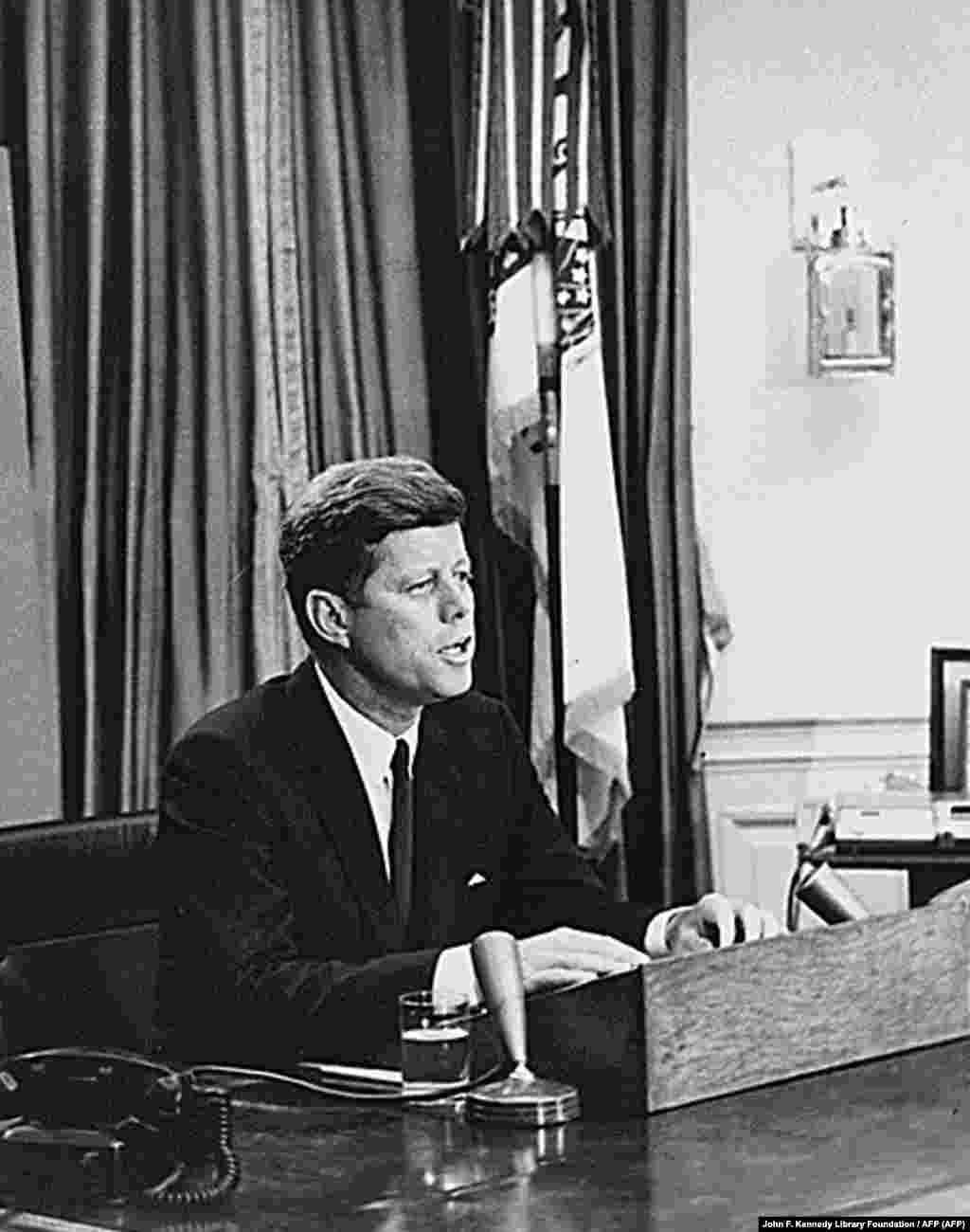 Kennedy kiállt az afroamerikaiak mellett a polgárjogi küzdelemben. A kép 1963. június 11-én készült, amikor erről tartotta híres beszédét a televízióban. Aznap reggel George Wallace, Alabama kormányzója az alabamai egyetem bejáratánál útját állta két színes bőrű diáknak, Vivien Malone-nak és James Hoodnak. A helyettes főügyész a nemzeti gárda segítségét kérte a kormányzó félreállításához.