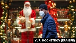 A man wearing a face mask walks in front of a shop window decorated for Christmas and New Year celebrations in Moscow. (illustrative photo)