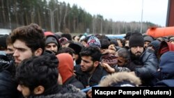 Migranti čekaju da dobiju hranu ispred transportnog i logističkog centra u blizini bjelorusko-poljske granice u regiji Grodno, Bjelorusija, 21. novembar 2021.