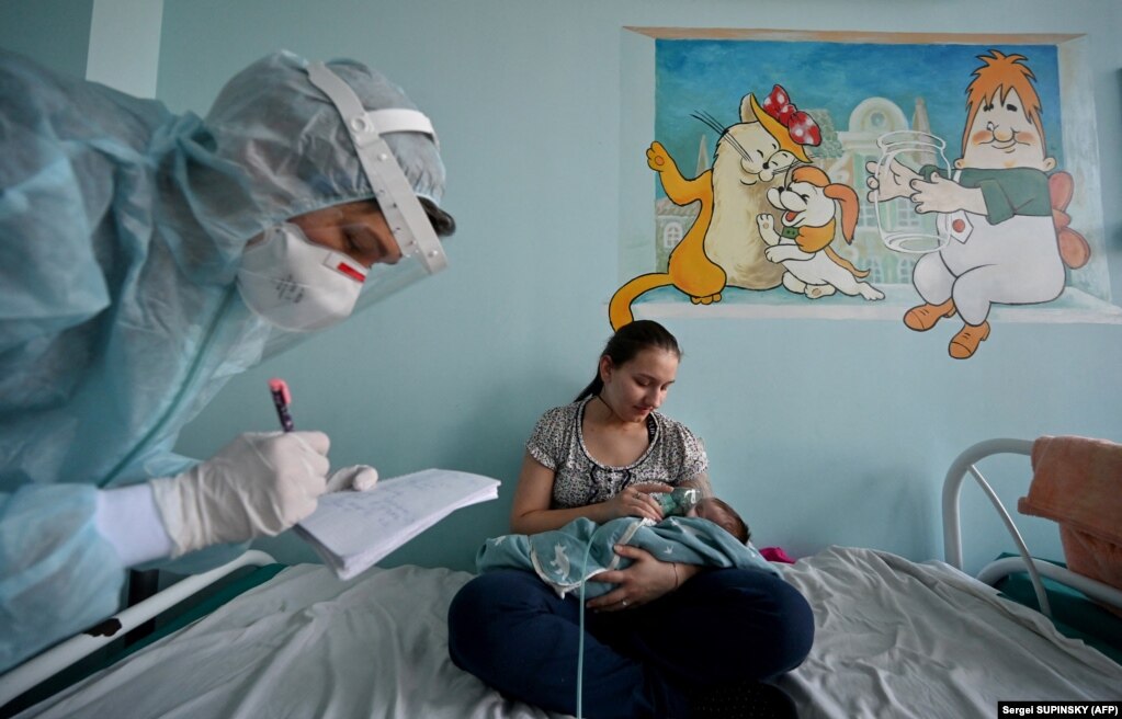 Një grua, duke mbajtur një maskë oksigjeni mbi fytyrën e bebes së saj, të sëmurë me koronavirus, në një dhomë të një spitali për fëmijë, në Kiev, Ukrainë, më 16 nëntor.