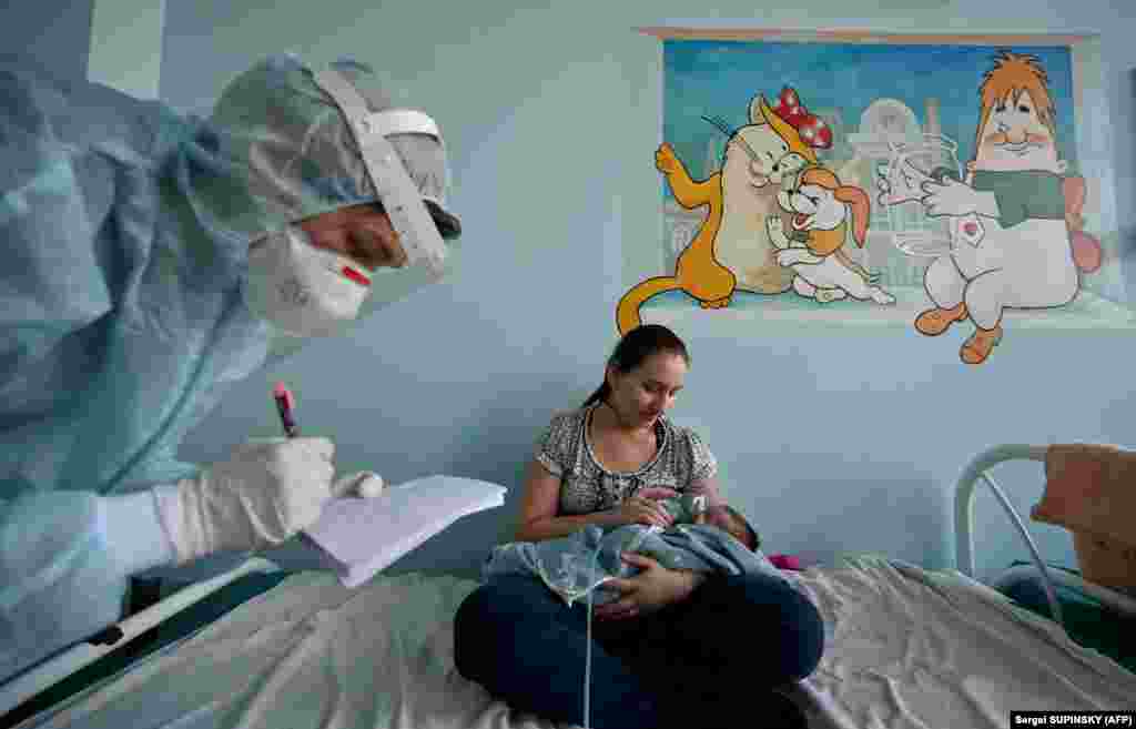 A woman holds an oxygen mask over the face of her baby who is suffering from COVID-19 in a children&#39;s hospital in Kyiv.&nbsp;