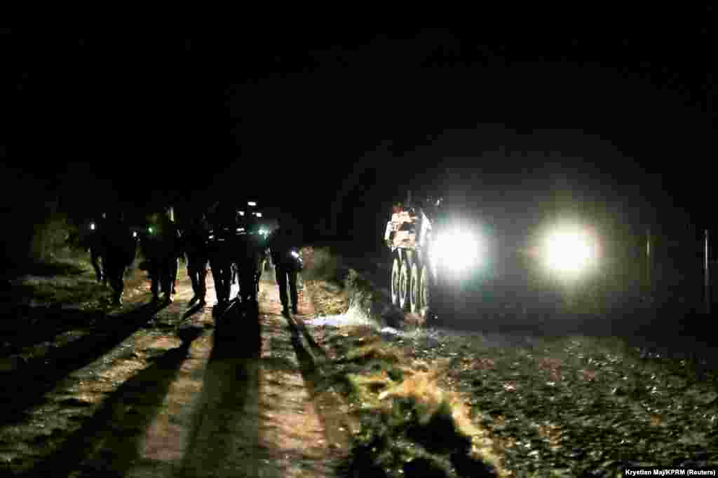 Polish service members walk next to an armored vehicle as Poland&#39;s Prime Minister Mateusz Morawiecki visits the border outside the town of Krynki, Poland, in this image released by the Polish prime minister&#39;s office on November 22, 2021.