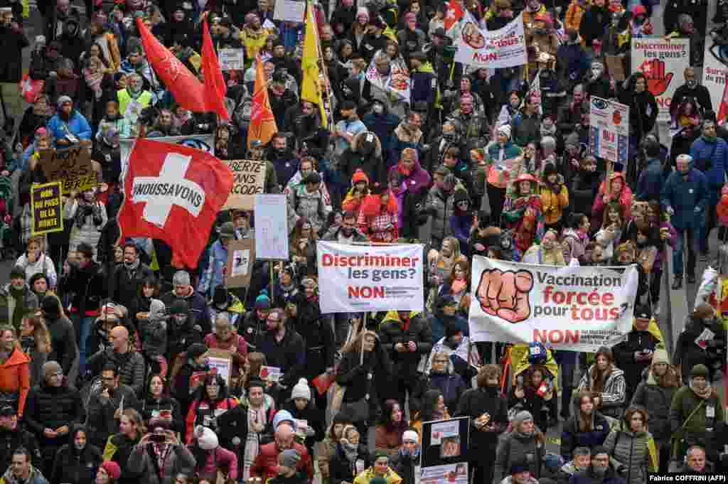 Demonstranti drže zastave i transparente tokom protesta u Lozani, u Švicarskoj, protiv mjera za borbu protiv korona virusa, COVID-pasoša i vakcinacije, 20. novembra 2021.