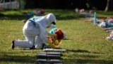 A cemetery worker puts flowers on the grave of a person, who died of the coronavirus disease in San Salvador, El Salvador November 2, 2021. 