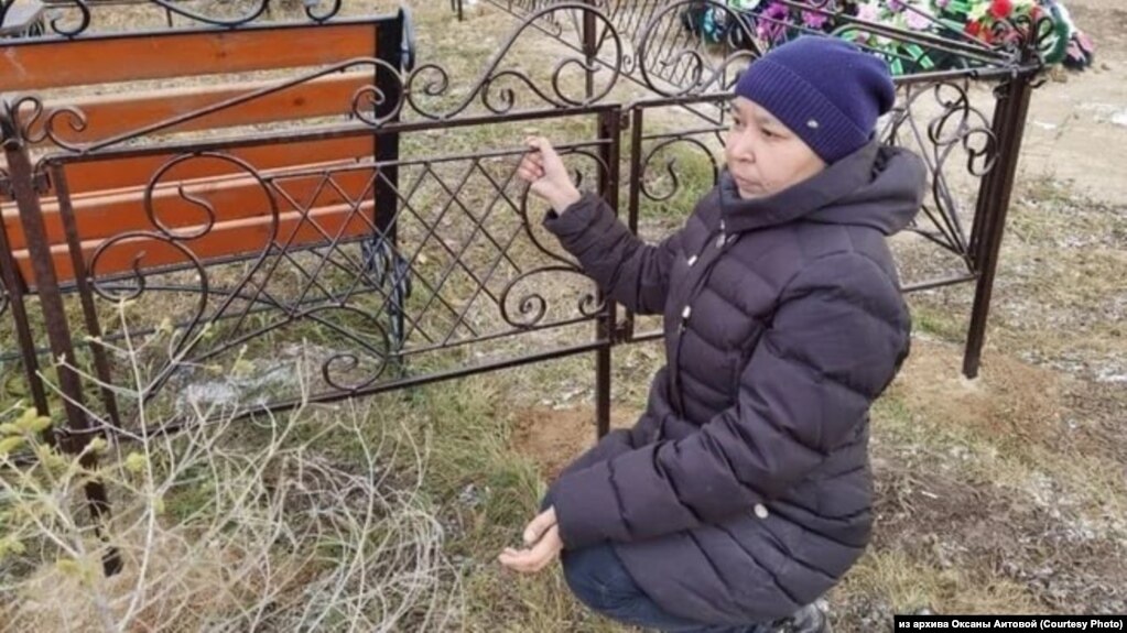 Оксана Аитова показывает, как полицейские пристегивали ее наручниками к ограде на кладбище