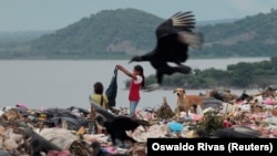 دو دختر بچه به دنبال پیدا کردن لباس در زباله‌های حاشیه ماناگوئا در اکتبر ۲۰۱۲