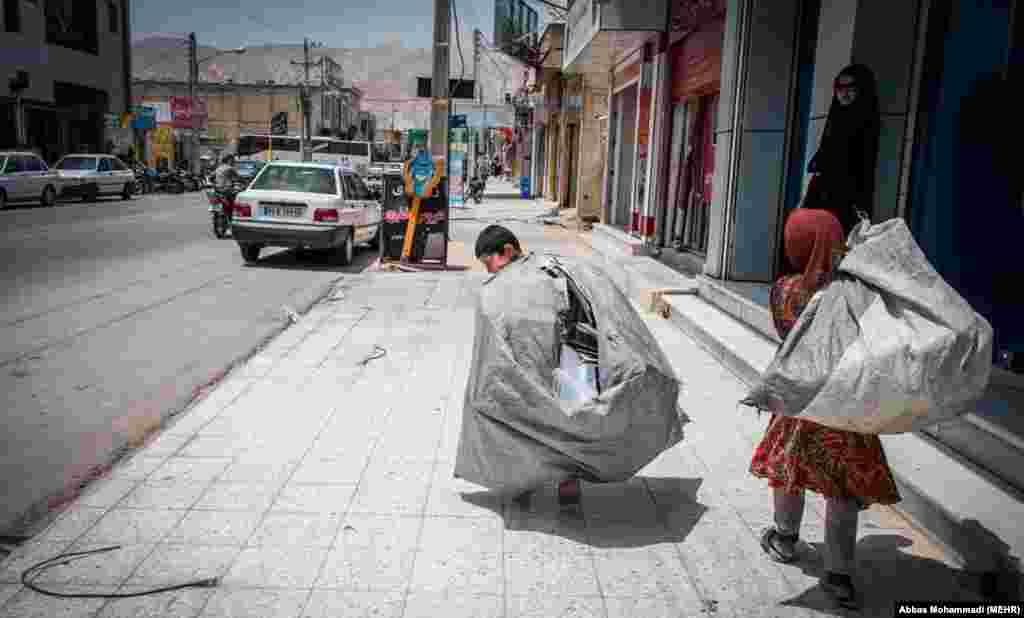 An Iranian boy and a girl carry sacks filled with recyclable materials, despite children under 15 being forbidden from working by Iranian law.