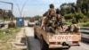 SYRIA - Security forces loyal to the interim Syrian government ride in the back of a vehicle moving along a road in the western city of Latakia on March 9, 2025. 