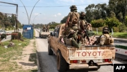 SYRIA - Security forces loyal to the interim Syrian government ride in the back of a vehicle moving along a road in the western city of Latakia on March 9, 2025. 