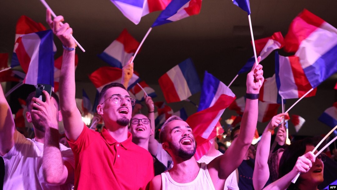 Susținătorii Rassemblement National (RN) flutură steagul Franței în timp ce fosta președintă a partidului, Marine Le Pen, ține un discurs, 30 iunie 2024.