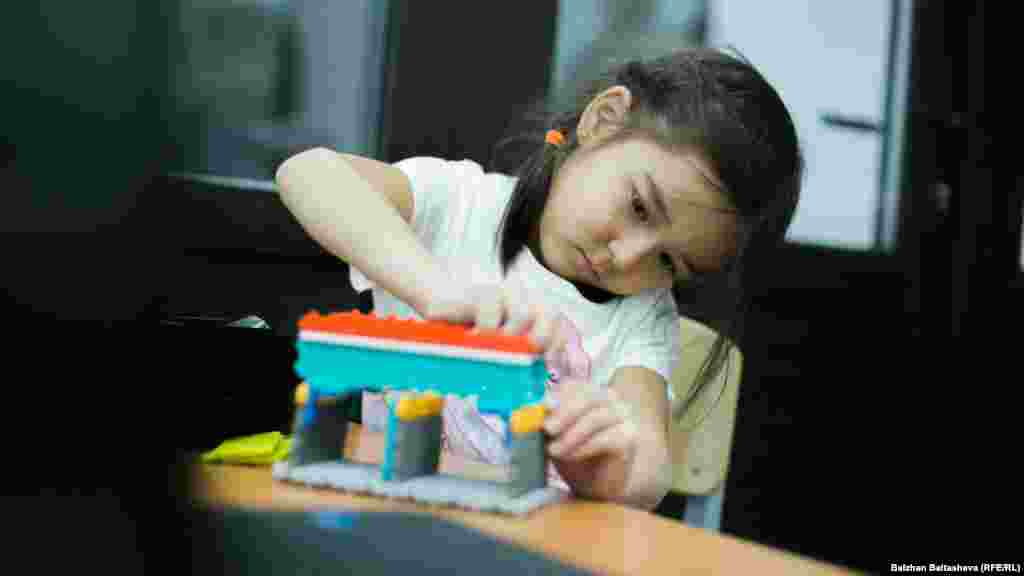Девочка собирает робота в детской школе по изготовлению роботов.