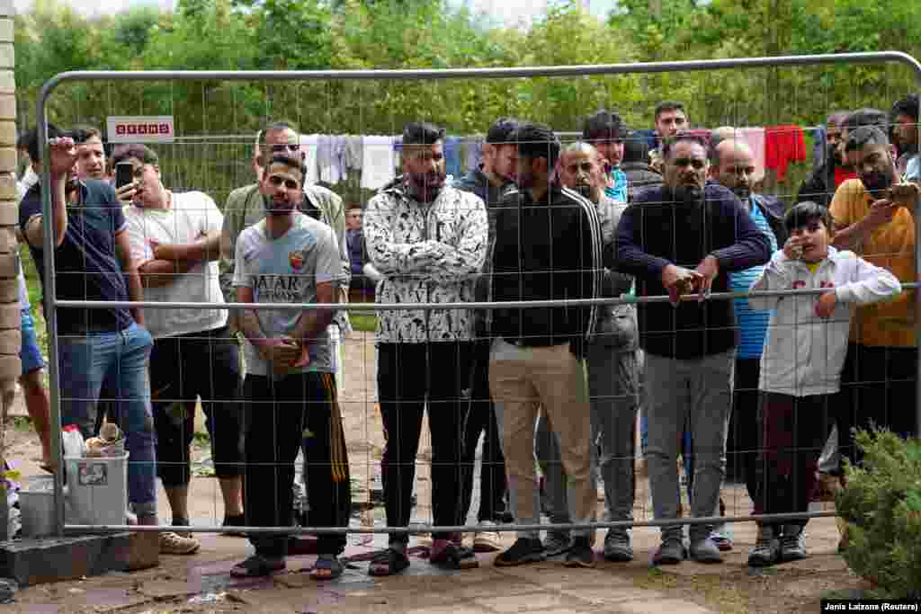 Migrants gather near a fence at a temporary detention center in Kazitiskis, Lithuania, on August 12. &nbsp; The stalemate on the Poland-Belarus border follows Lithuania&#39;s decision in early August to physically force migrants back into Belarus after more than 4,000 illegally entered that Baltic country from Belarus in the space of a few months in 2021. &nbsp; &nbsp;