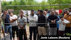 Migrants gather near a fence at a temporary detention center in Kazitiskis, Lithuania, on August 12.