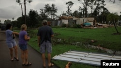 Tre njerëz duke shikuar pasojat nga uragani Milton në Florida.