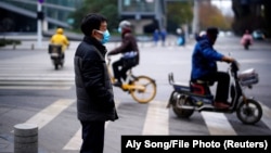 Люди на улице в китайском городе Ухань, где в конце 2019 года впервые был выявлен коронавирус.
