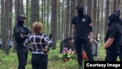 Люди в черном окружили женщину, пришедшую на акцию памяти в Сандармохе