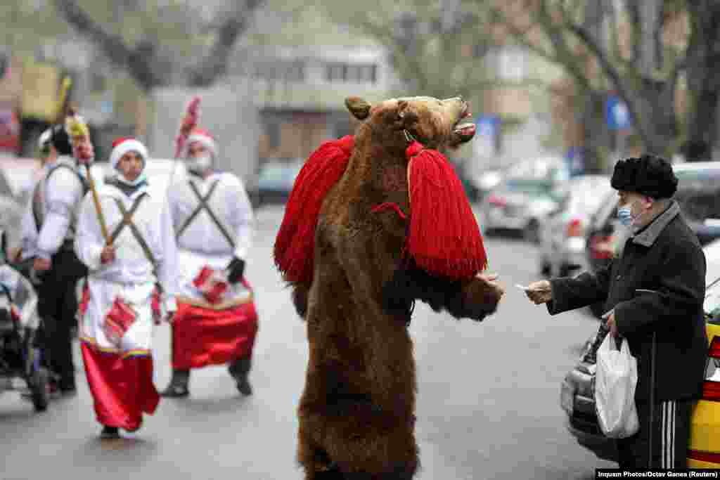A street performer dressed as a bear collects donations from passersby in central Bucharest, Romania. (Reuters/Octav Ganea)