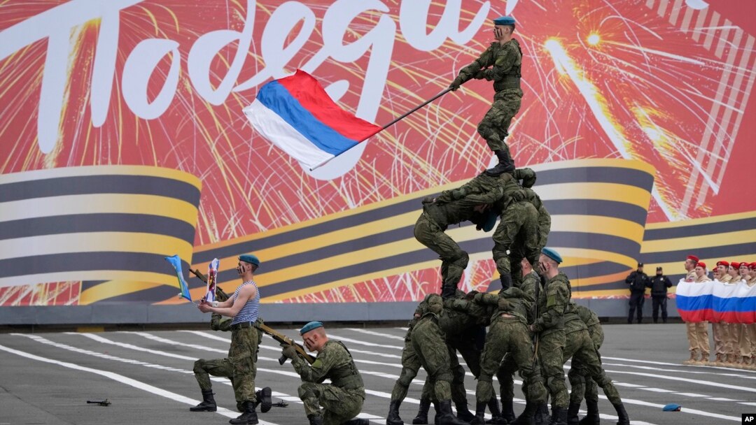 Cadeți militari în timpul repetițiilor pentru parada militară de Ziua Victoriei, prin care Rusia marchează în acest an 78 de ani de la victoria în cel de-al Doilea Război Mondial, în Sankt Petersburg, 7 mai 2023. Scrierea în limba rusă de pe afiș înseamnă „victorie”.
