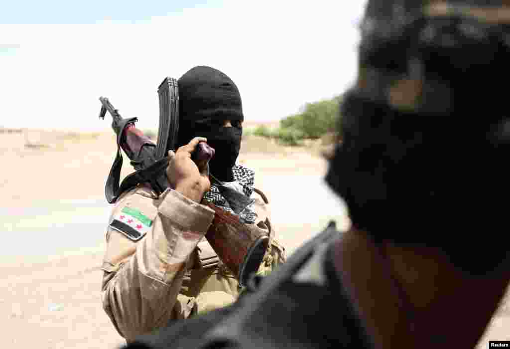 Syria -- A Syrian Democratic Forces (SDF) fighter carries his weapon as he stands near Raqqa city, June 14, 2017