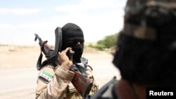 Syria -- A Syrian Democratic Forces (SDF) fighter carries his weapon as he stands near Raqqa city, June 14, 2017