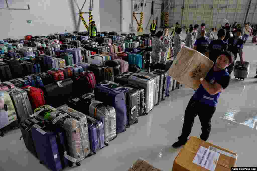 A worker at an air base in Manila helps to sort the luggage of Filipinos arriving back to their country after a repatriation flight out of the United Arab Emirates on March 19.