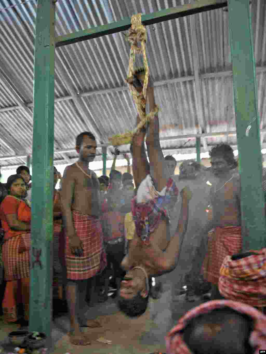 Індуіст ў вёсцы Байнан каля Калькуты вісіць над вогнішчам падчас традыцыйнага рытуалу ў гонар бога Шывы.