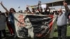 A man and woman hold up a banner depicting the image of Mahsa Amini, who died while in the custody of Iranian authorities, during a demonstration denouncing her death by Iraqi and Iranian Kurds outside the UN offices in Irbil, the capital of Iraq's autonomous Kurdish region, on September 24.