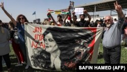 A man and woman hold up a banner depicting the image of Mahsa Amini, who died while in the custody of Iranian authorities, during a demonstration denouncing her death by Iraqi and Iranian Kurds outside the UN offices in Irbil, the capital of Iraq's autonomous Kurdish region, on September 24.