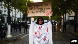 یک معترض ایرانی در تجمع روز یکشنبه در پاریس که پلاکاردی با این نوشته در دست دارد: «این تصویر مردم من است. صدای ایرانی‌ها را به گوش همه برسانید»