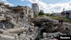 Local residents stand next to the debris of a destroyed building in Lysychansk on September 21.