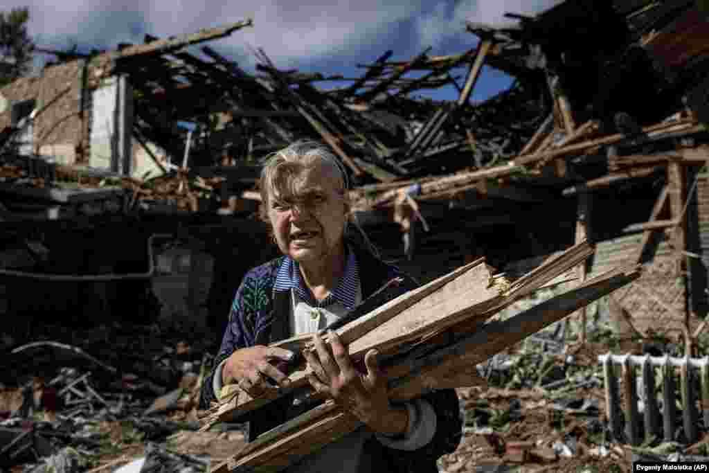 A woman collects firewood from a destroyed school where occupying Russian forces had been based in the recently retaken Ukrainian city of Izyum.&nbsp;