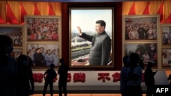 People stand in front of images of Chinese President Xi Jinping at the Museum of the Communist Party of China in Beijing on September 4.