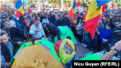 Simpatizanți ai Partidului Șor conduși de președintele raionului Orhei, Dinu Țurcanu (purtând ie) instalează corturi în fața Președinției și Parlamentului, la un protest pe 18 septembrie 2022, în timp ce liderii partidului sunt cercetați penal în dosare de corupție.