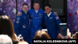 NASA astronaut Frank Rubio (right) and Russian cosmonauts Sergei Prokopyev (center) and Dmitry Petelin pose in front of a bus while leaving a hotel for prelaunch preparations on September 21.