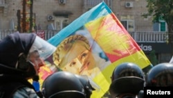 Ukrainian riot police block opposition supporters carrying a flag with the portrait of jailed former Prime Minister Yulia Tymoshenko from entering the city hall during a rally in Kyiv in July.