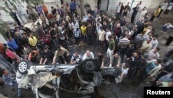 Palestinians gather around a destroyed car after what witnesses said was an Israeli air strike in Gaza City on November 20.