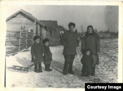 Copilărie în Siberia. Iarna anului 1956. Familia Ghieș, în fața casei lor din bârne: Vasile, Maria și fiii lor: Teodor, Victor și Grigore, născuți în locul de deportare