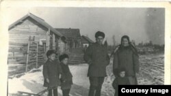 Copilărie în Siberia. Iarna anului 1956. Familia Ghieș, în fața casei lor din bârne: Vasile, Maria și fiii lor: Teodor, Victor și Grigore, născuți în locul de deportare