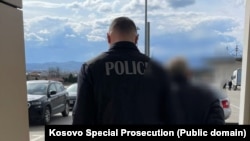 Një zyrtar i Policisë së Kosovës e shoqëron një burrë të arrestuar për krime lufte në Kosovë më 1998-1999.